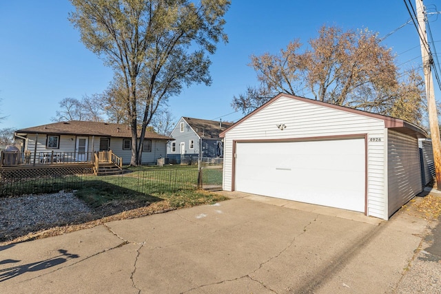 view of front of home with a front yard, a detached garage, fence, and an outdoor structure