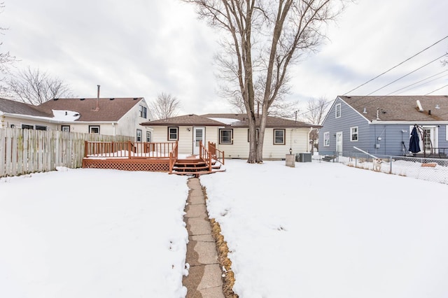 snow covered rear of property with fence, a deck, and central AC