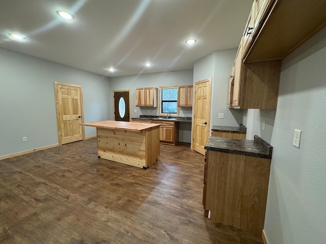 kitchen featuring recessed lighting, a sink, a kitchen island, baseboards, and dark wood finished floors