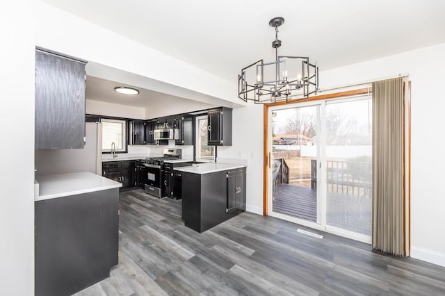 kitchen with dark wood finished floors, light countertops, appliances with stainless steel finishes, dark cabinetry, and a sink