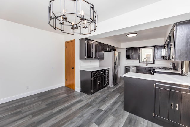 kitchen featuring dark wood-type flooring, a notable chandelier, stainless steel appliances, light countertops, and baseboards