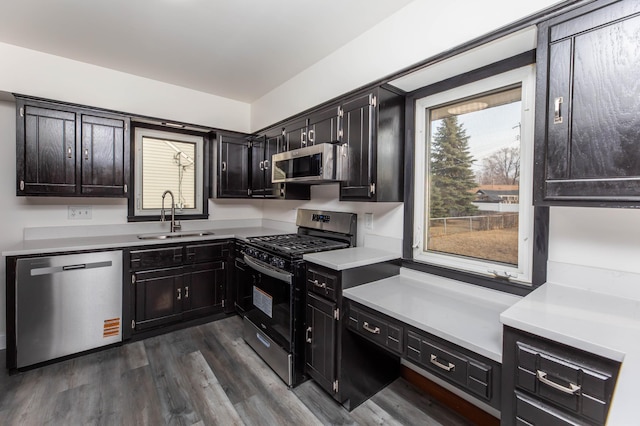 kitchen with a sink, light countertops, dark wood-style flooring, and stainless steel appliances