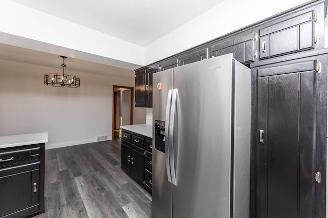 kitchen featuring stainless steel refrigerator with ice dispenser, an inviting chandelier, light countertops, baseboards, and dark wood-style flooring