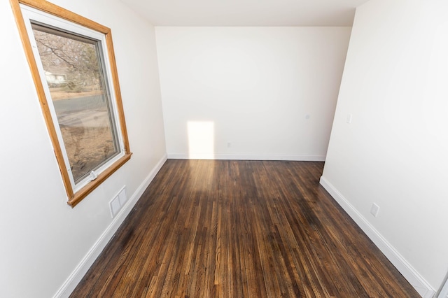 empty room featuring visible vents, baseboards, and wood finished floors