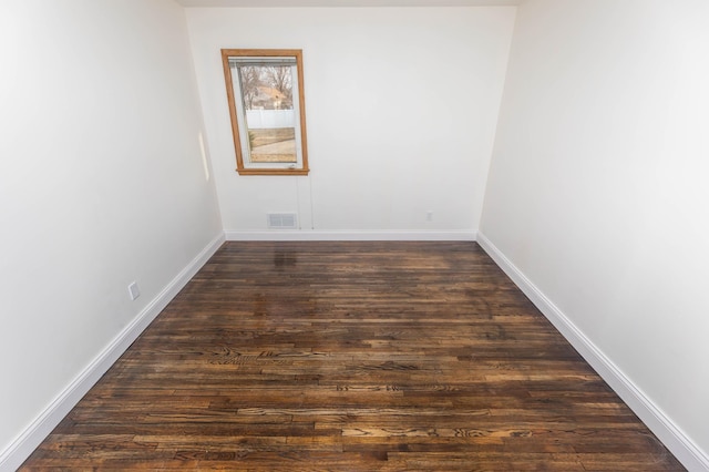 empty room featuring dark wood-type flooring, baseboards, and visible vents