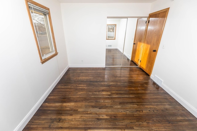 hallway featuring wood finished floors, visible vents, and baseboards