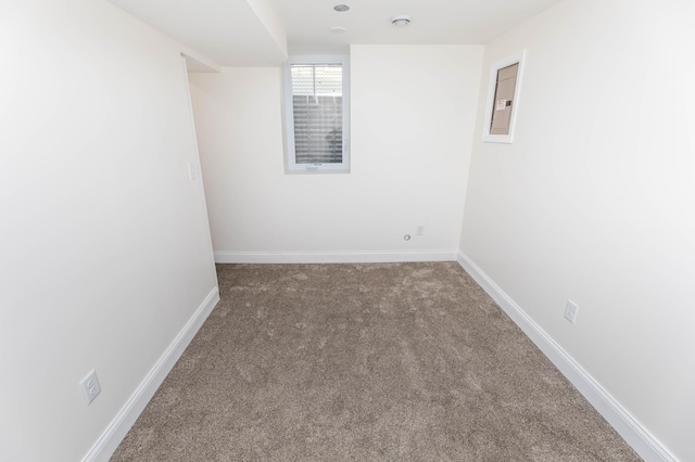 carpeted spare room featuring electric panel and baseboards