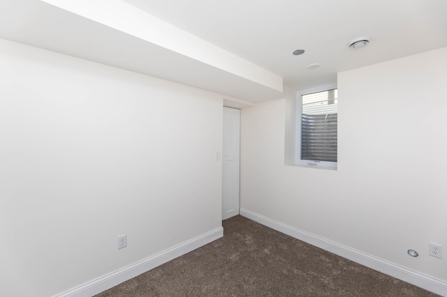 empty room with baseboards and dark colored carpet