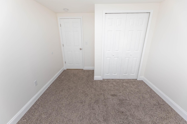 unfurnished bedroom with a closet, carpet flooring, and baseboards