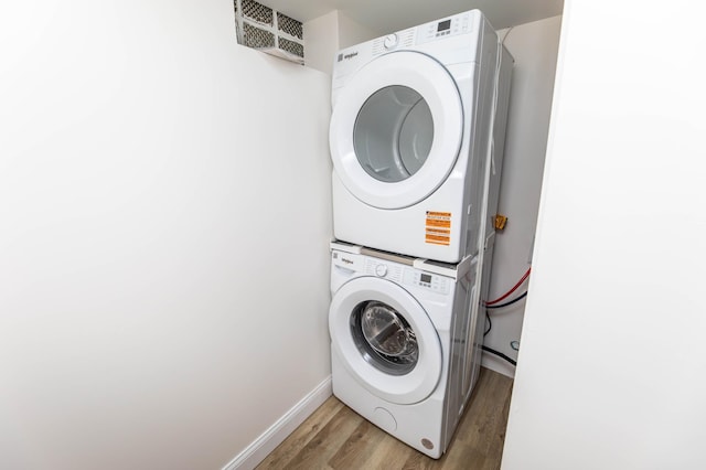 clothes washing area featuring stacked washer / dryer, visible vents, baseboards, laundry area, and light wood-style floors