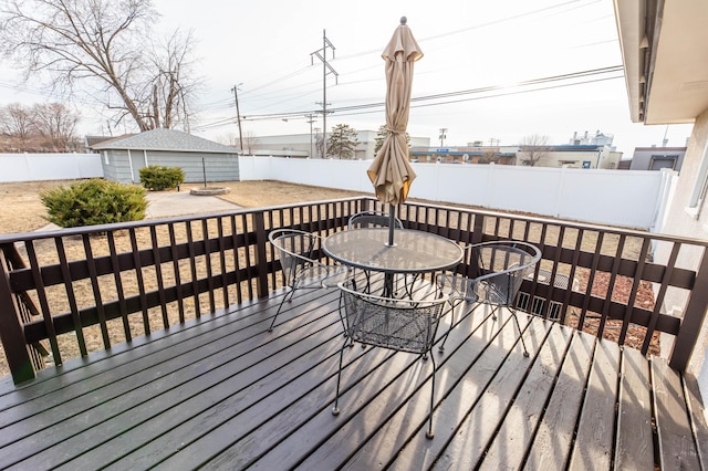 wooden terrace featuring an outdoor structure, outdoor dining area, and a fenced backyard