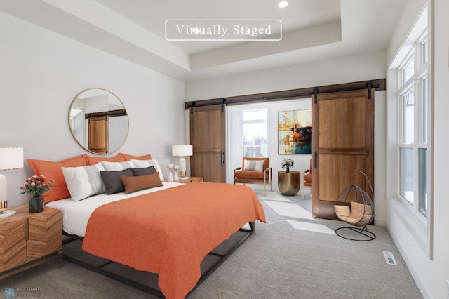 carpeted bedroom with a barn door, multiple windows, recessed lighting, and a raised ceiling