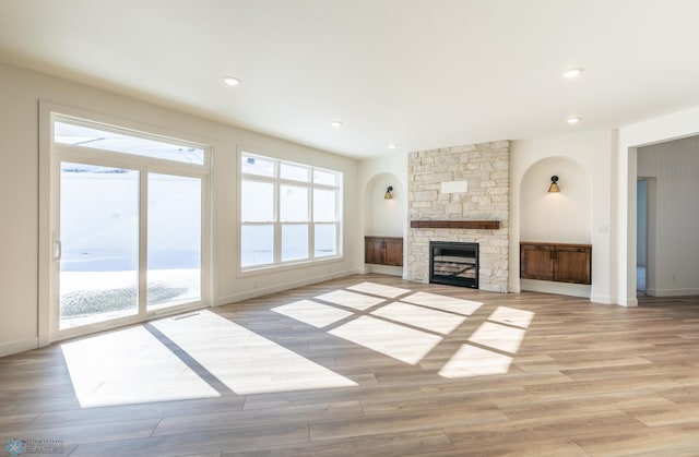 unfurnished living room with a stone fireplace, light wood finished floors, baseboards, and recessed lighting