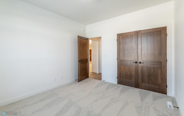 unfurnished bedroom featuring baseboards, carpet flooring, and a closet