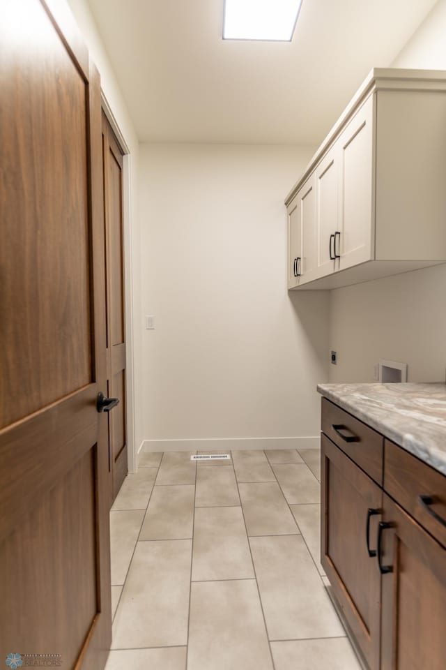 washroom featuring cabinet space, baseboards, hookup for an electric dryer, and light tile patterned floors