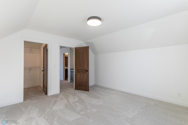 additional living space featuring vaulted ceiling, light colored carpet, and baseboards