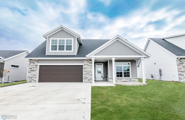craftsman-style home with stone siding, a front yard, and board and batten siding
