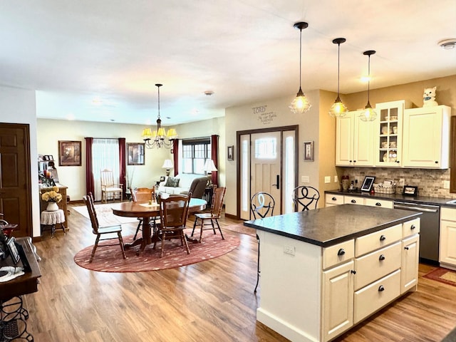 kitchen with dark countertops, glass insert cabinets, dishwasher, and hanging light fixtures