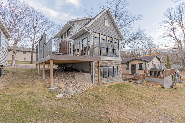 rear view of house featuring stone siding, a lawn, and a wooden deck