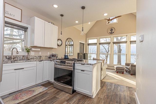 kitchen featuring light stone counters, a peninsula, white cabinets, stainless steel range with gas cooktop, and pendant lighting