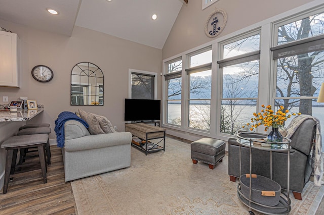 living area with high vaulted ceiling, recessed lighting, baseboards, and wood finished floors