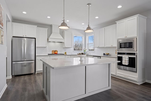 kitchen featuring custom exhaust hood, a kitchen island, dark wood finished floors, and stainless steel appliances