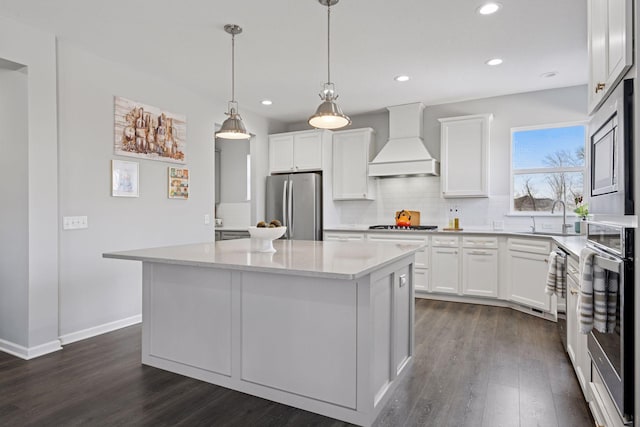 kitchen with tasteful backsplash, premium range hood, dark wood finished floors, appliances with stainless steel finishes, and a sink