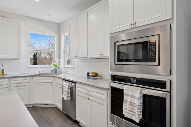 kitchen featuring a sink, tasteful backsplash, white cabinetry, and stainless steel appliances