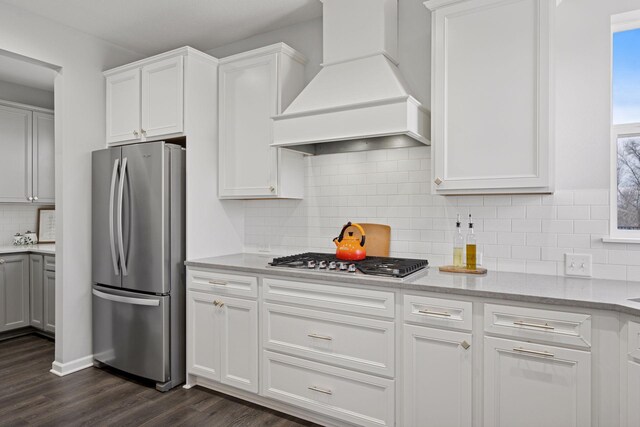 kitchen with premium range hood, dark wood finished floors, decorative backsplash, stainless steel appliances, and white cabinetry