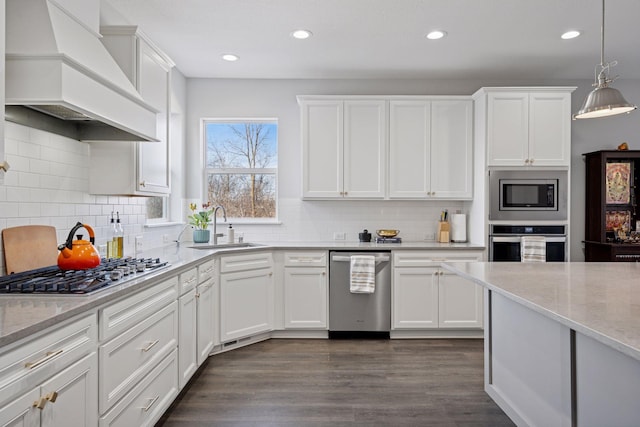 kitchen featuring a sink, custom range hood, stainless steel appliances, white cabinetry, and dark wood-style flooring