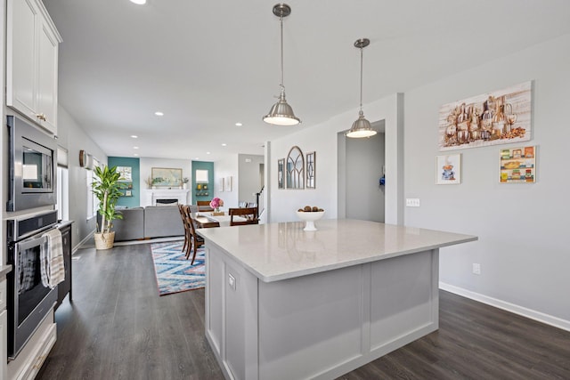 kitchen featuring a kitchen island, dark wood finished floors, a fireplace, stainless steel appliances, and white cabinets