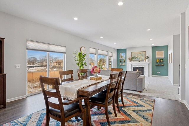 dining room with recessed lighting, baseboards, wood finished floors, and a glass covered fireplace