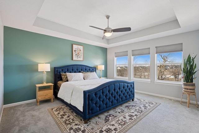 bedroom featuring multiple windows, a raised ceiling, carpet floors, and baseboards