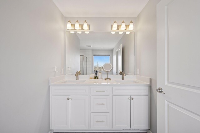 bathroom with a sink, a shower stall, and double vanity