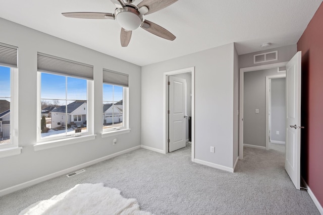 unfurnished bedroom featuring carpet, baseboards, visible vents, and a ceiling fan