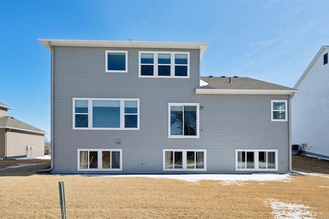 back of property featuring central air condition unit and a lawn