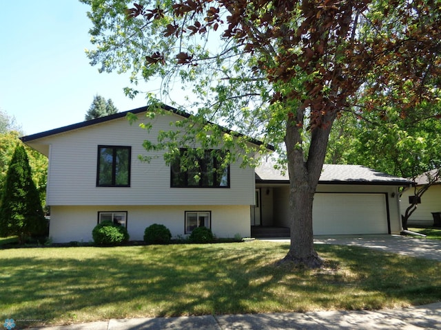 tri-level home with concrete driveway, an attached garage, and a front yard