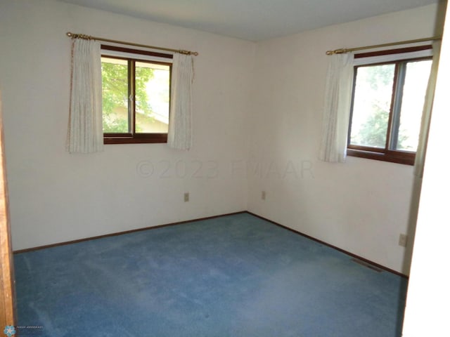 unfurnished room with visible vents, baseboards, and dark colored carpet