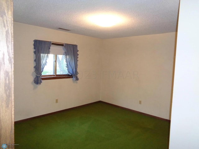 spare room with visible vents, baseboards, dark colored carpet, and a textured ceiling