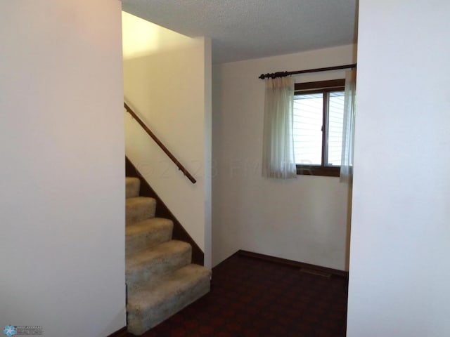 stairs with a textured ceiling and baseboards