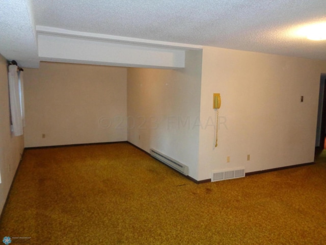 spare room featuring visible vents, baseboards, carpet, a textured ceiling, and a baseboard heating unit