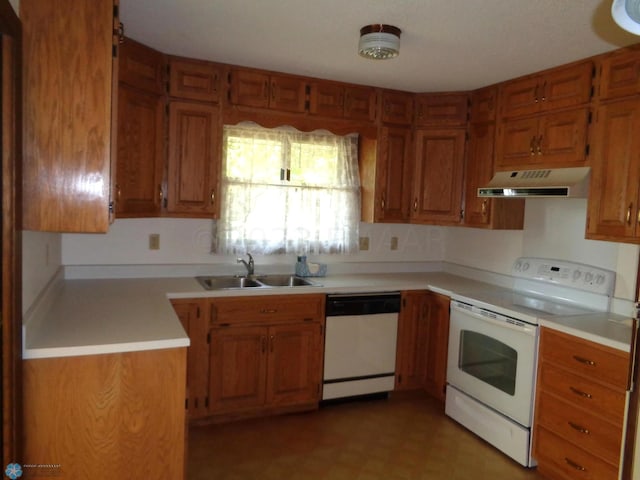 kitchen with white appliances, under cabinet range hood, light countertops, and a sink