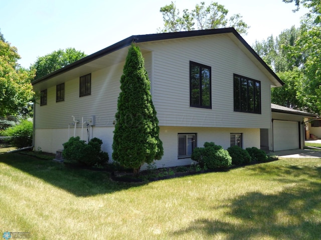 view of side of property with driveway, brick siding, a lawn, and an attached garage