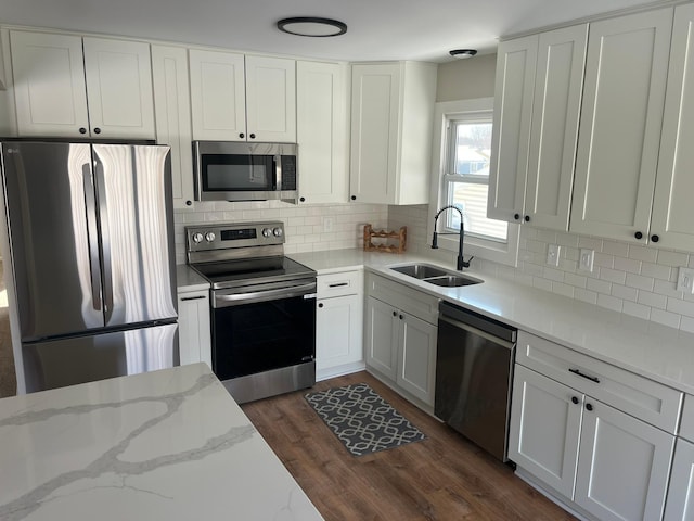 kitchen with dark wood-style floors, stainless steel appliances, backsplash, white cabinets, and a sink