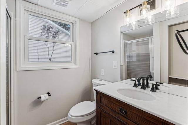 bathroom with a stall shower, visible vents, vanity, and toilet