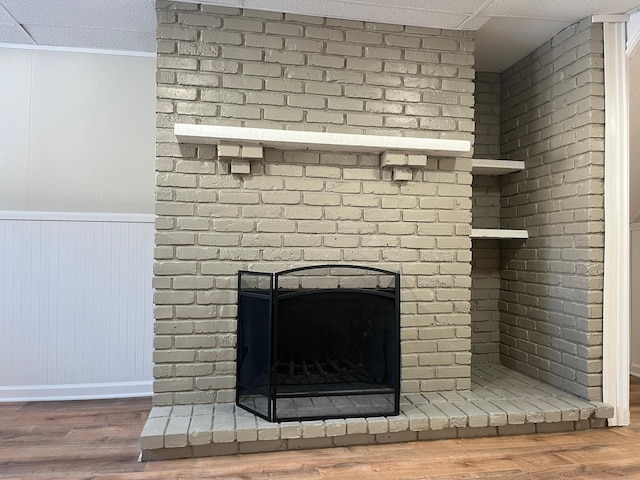 details with a brick fireplace and wood finished floors