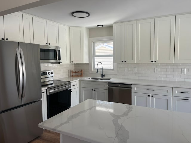 kitchen with appliances with stainless steel finishes, a sink, white cabinets, and decorative backsplash