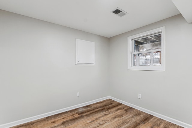 empty room featuring baseboards, visible vents, and wood finished floors