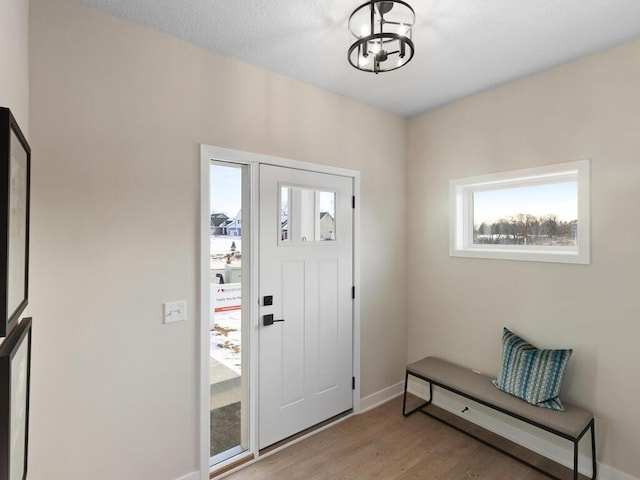 entrance foyer featuring baseboards, a chandelier, and light wood-style floors