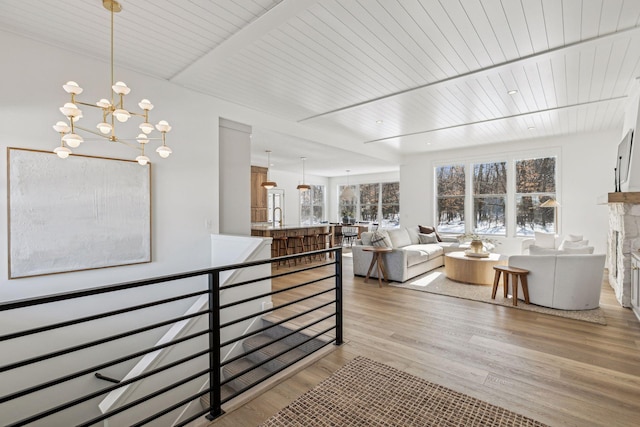 living room featuring light wood-style floors, wood ceiling, a fireplace, and an inviting chandelier